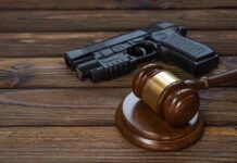 Gavel and gun on wooden table.