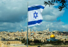 Israeli flag flying over Jerusalem skyline with Dome of Rock.