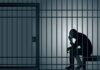 Silhouette of a person sitting in a jail cell.