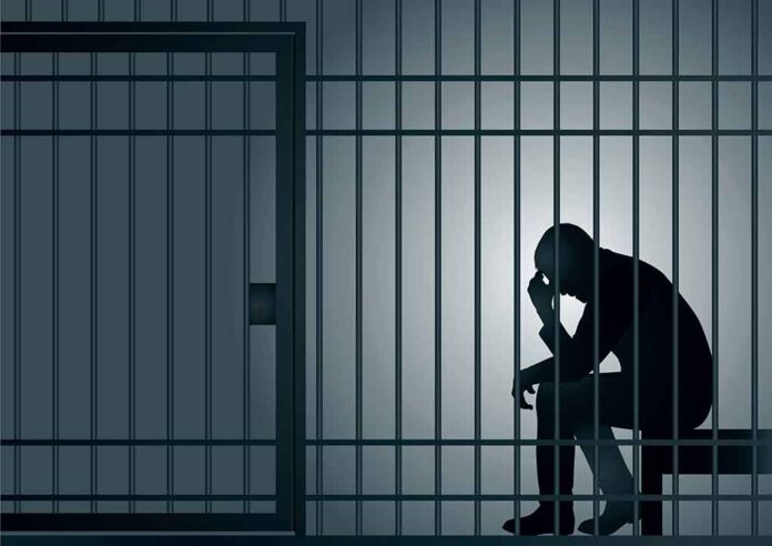 Silhouette of a person sitting in a jail cell.