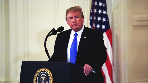 Donald Trump speaking at a podium with American flag.