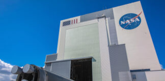 NASA building with rocket booster being transported outside.