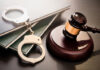 Gavel, handcuffs, and legal books on a dark surface.