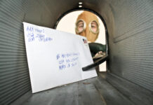 Envelope inside mailbox with person wearing mask outside.