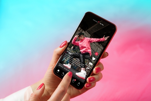 Person viewing dancing video on smartphone with colorful background.