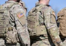 Soldiers in camouflage uniforms with American flag patches.