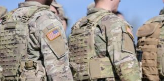 Soldiers in camouflage uniforms with American flag patches.