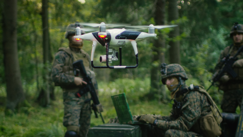 Soldiers in a forest operating a drone.