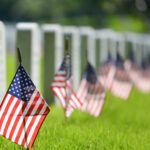 Abandoned Veterans FINALLY Honored — Bureaucracy Exposed… American flags beside gravestones in a cemetery.