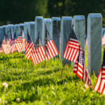 Radioactive Grave HAUNTS Arlington National Cemetery…. Rows of white headstones with small American flags in a sunlit cemetery