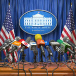 Political Elite’s DARK SIDE – Cloobeck’s SCANDAL Press briefing podium with many microphones at a government venue