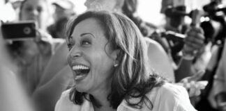 A smiling woman in a crowd, black and white.