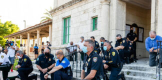 Police officers kneeling on steps, some wearing face masks.