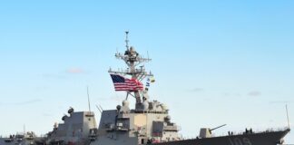 naval destroyer with flags sailing on open water