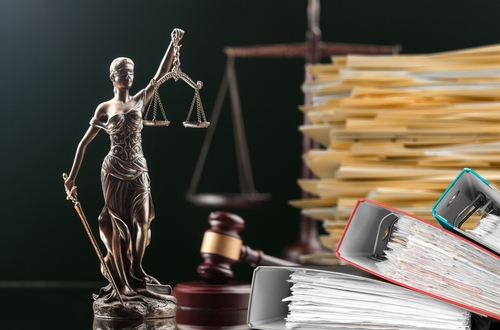 A statue of Lady Justice holding scales, surrounded by legal documents and a gavel