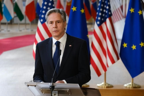 Man in suit speaking at podium with international flags behind