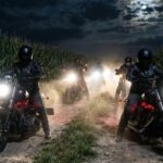 Motorcycle riders in a cornfield at night with headlights on