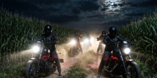 Motorcycle riders in a cornfield at night with headlights on