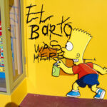 Graffiti of Bart Simpson writing El Barto was here on a yellow wall
