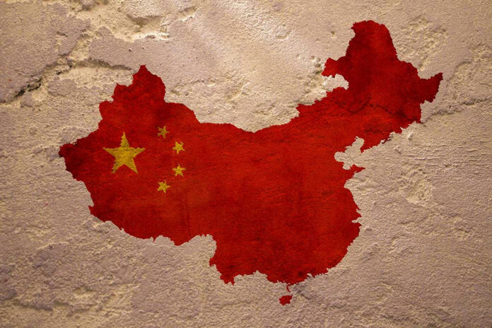 409776640 Chinas map with flag painted on textured wall.