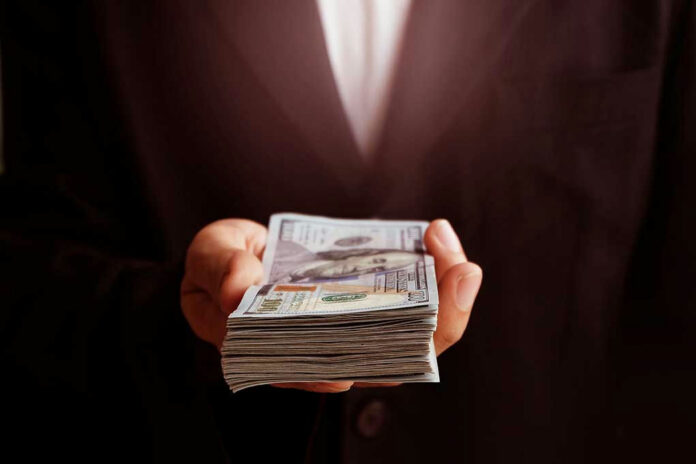 719123734 Hand holding a stack of US dollars.