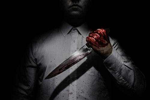 shutterstock1051839950-1jpg Person holding bloody knife in dark lighting.