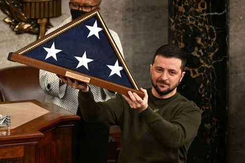 shutterstock2250551125jpg Man holding folded American flag in wooden case.