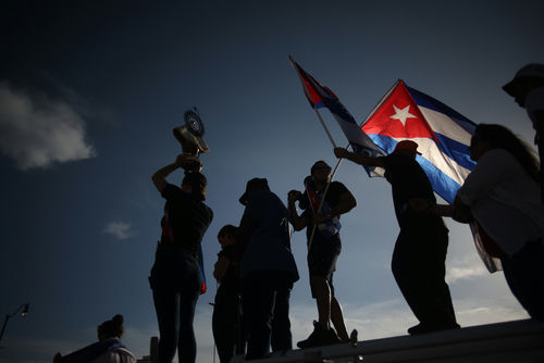 shutterstock_2006478167 Silhouetted crowd waving Cuban flags at dusk