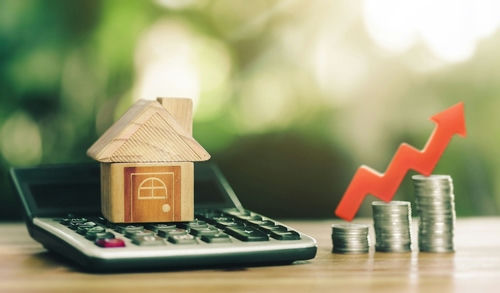 Toy house, calculator, coins, and red upward arrow.