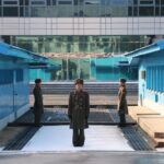 Dealmaker Drafted: Seoul Presses Trump Two hands of individuals facing each other with flags of China and the USA on the table