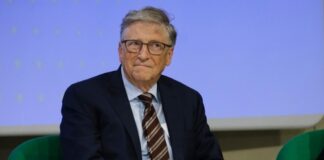 A man in a suit sitting on a green chair during a conference