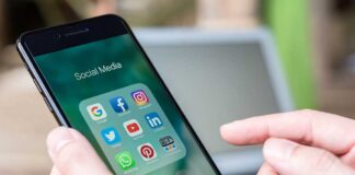 Person holding smartphone with social media app folder open