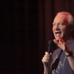 Maher Says Artist Boycott Hands Trump a Win A comedian performing on stage with a microphone in hand