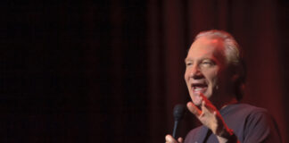 A comedian performing on stage with a microphone in hand