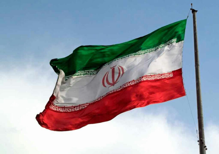 1088416085-1 Iranian flag flying against a clear sky.