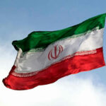 Iranian flag flying against a clear sky.