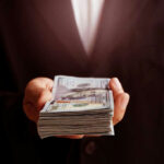 Hand holding a stack of US dollars.