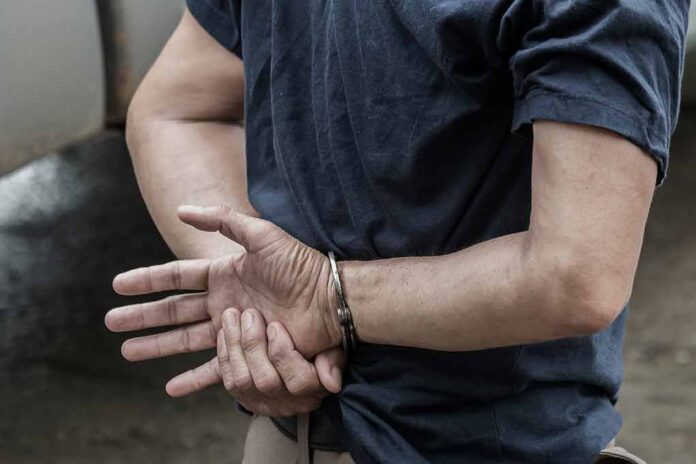 shutterstock_1115333126 person in handcuffs with hands behind back