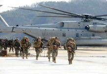 Night Sky Erupts—Missiles Target US Hub Soldiers disembark and walk past a large military helicopter