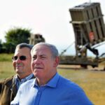 two men standing near a missile defense launcher outdoors