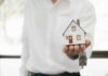 Rent Caps Ignite Property Rights Brawl Hand holding a small house model and house-shaped key