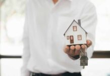 Rent Caps Ignite Property Rights Brawl Hand holding a small house model and house-shaped key