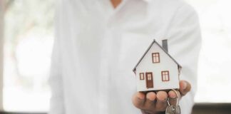 Hand holding a small house model and house-shaped key