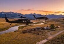 Black Hawks Storm Flooded Kids’ Camp Two military helicopters flying over a rural landscape at sunset