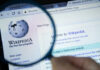 Wikipedia homepage viewed through a magnifying glass.