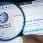 Wikipedia homepage viewed through a magnifying glass.